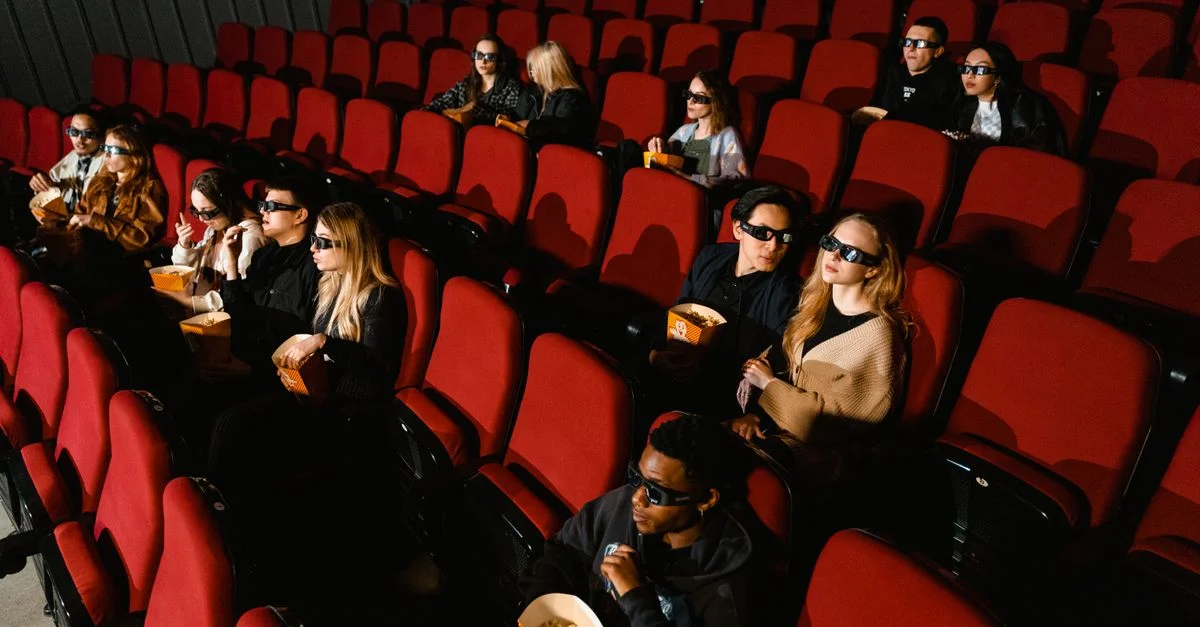 Des personnes profitant d'un film au cinéma, portant des lunettes 3D et mangeant du popcorn.