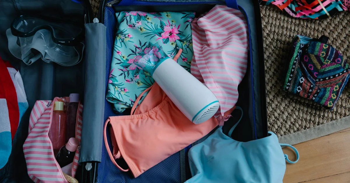 Une valise remplie de maillots de bain, de lunettes de protection et d'éléments essentiels pour un voyage d'été.