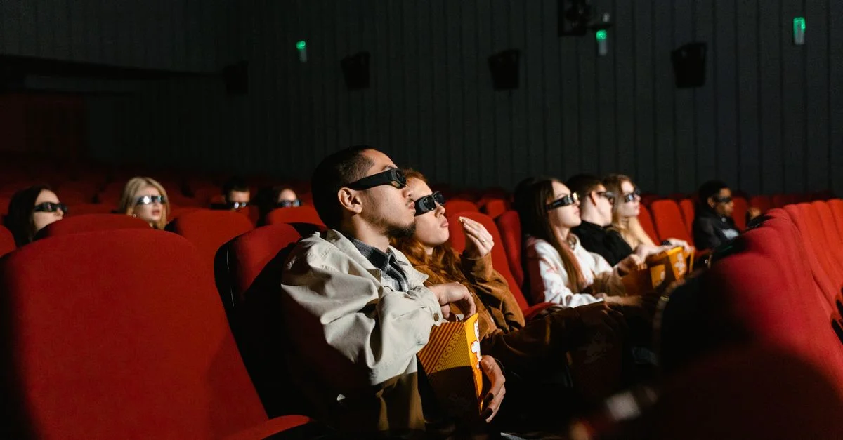 Des personnes regardant un film 3D dans une salle, avec du popcorn à la main, totalement immergées.
