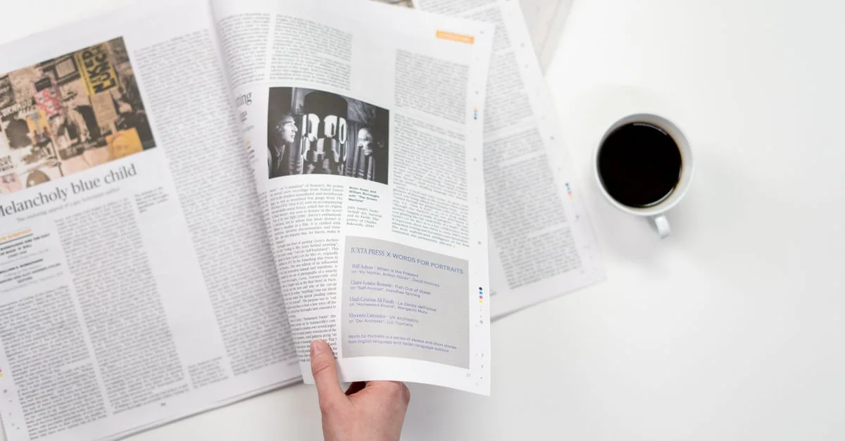 Un gros plan d'une main tenant un journal avec une tasse de café sur une surface blanche.