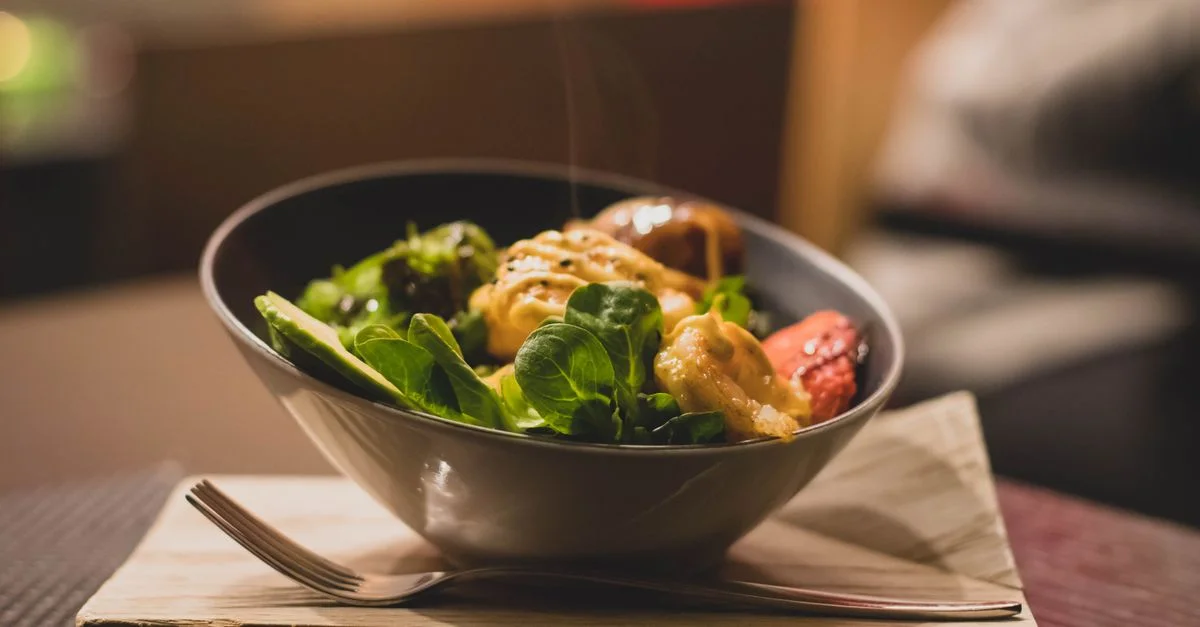 Délicieux bol de salade avec des légumes frais et du poulet grillé servi sur un plateau en bois.