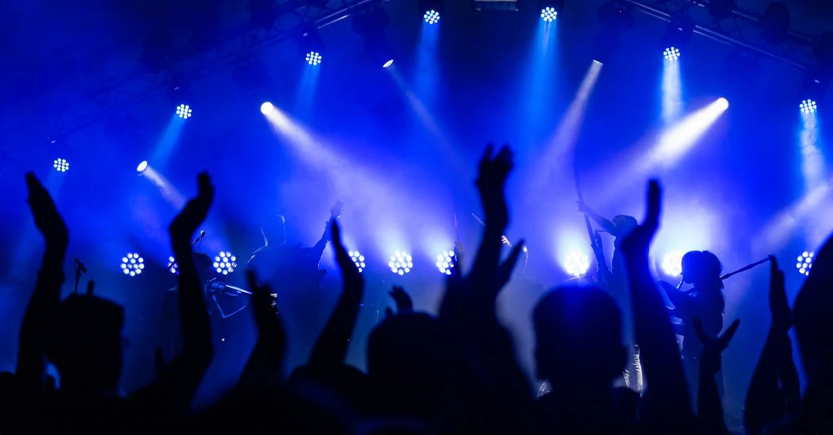 Scène de concert dynamique avec une foule enjouée et des lumières bleues vibrantes.