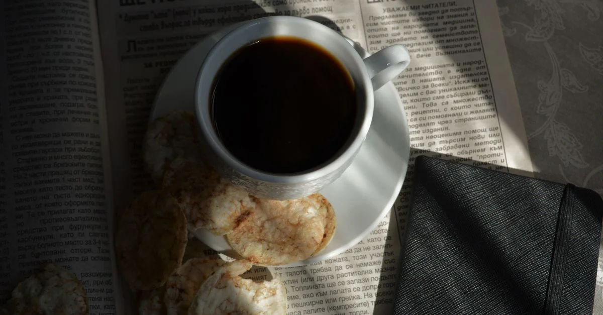 Une ambiance chaleureuse avec une tasse de café noir, des biscuits et un journal, idéale pour un matin détendu.