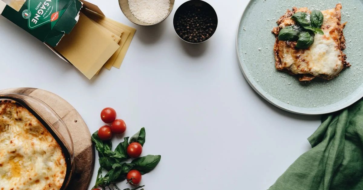 Délicieuse lasagne italienne maison avec des tomates fraîches et du basilic, présentée sur un fond blanc.